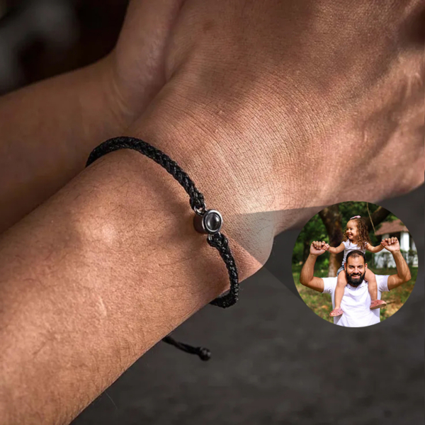 Hombre llevando pulsera de cuerda negra proyectando foto familiar