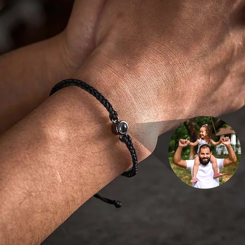 Hombre llevando pulsera de cuerda negra proyectando foto familiar